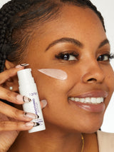 Woman applying a skincare product to her face with a visible brand name.