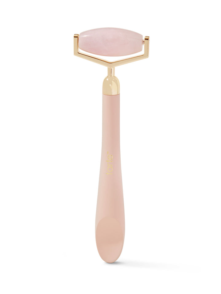 Pink facial roller with gold accents on a white background