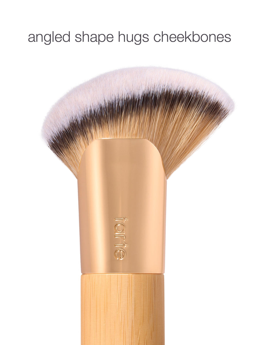 Makeup brush with wooden handle and pink bristle head on a white background