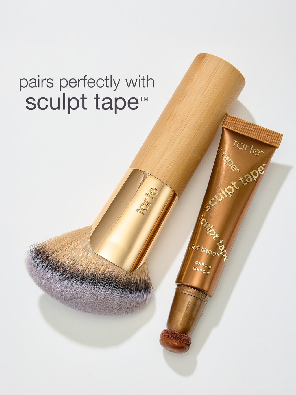 Makeup brush and 'sculpt tape' by tarte on a light gray background
