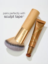 Makeup brush and 'sculpt tape' by tarte on a light gray background
