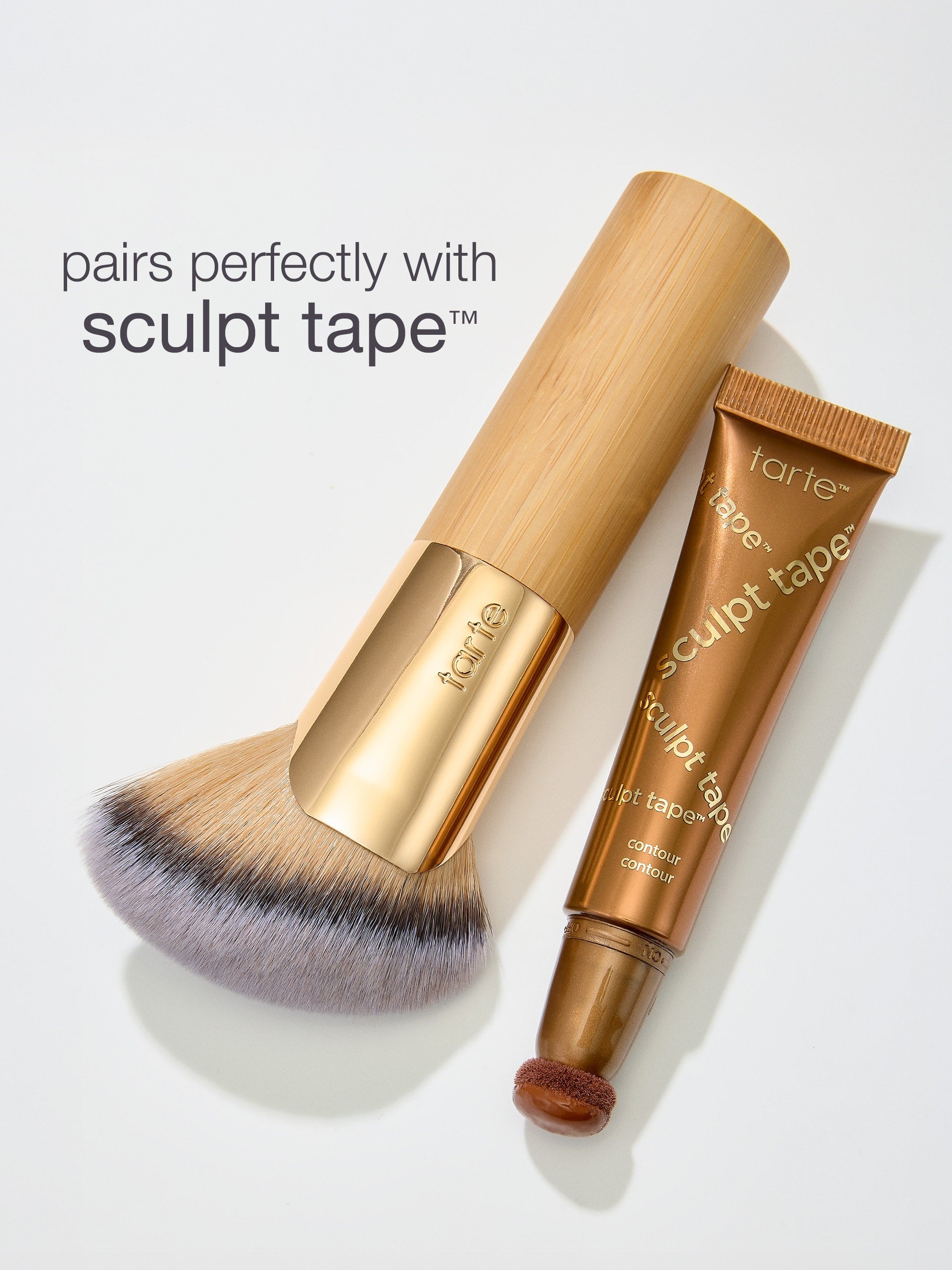 Makeup brush and 'sculpt tape' by tarte on a light gray background