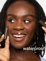 A person applies Tarte Cosmetics product to eyebrows, smiling in a close-up setting. The product is labeled busy gal brows. Background is white, and the word waterproof is displayed.