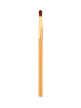 A makeup brush with a wooden handle and soft, dense bristles is positioned vertically against a plain white background. The gold ferrule is engraved with tarte.
