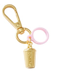 Gold keychain with a coffee cup charm and pink ring on a white background