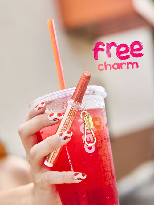 Hand holding a red drink with a straw and a lip balm, featuring 'free charm' branding.