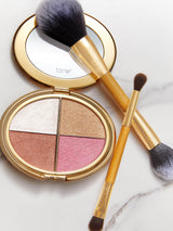 Makeup compact with blush shades and two brushes on a marble surface