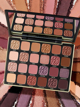 Makeup palette with various shades of eyeshadows on a colorful background