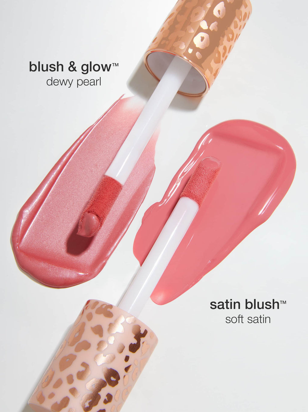 Two lip gloss applicators with leopard print handles lay on a white surface, showcasing swatches. Text reads: blush & glow™ dewy pearl and satin blush™ soft satin.