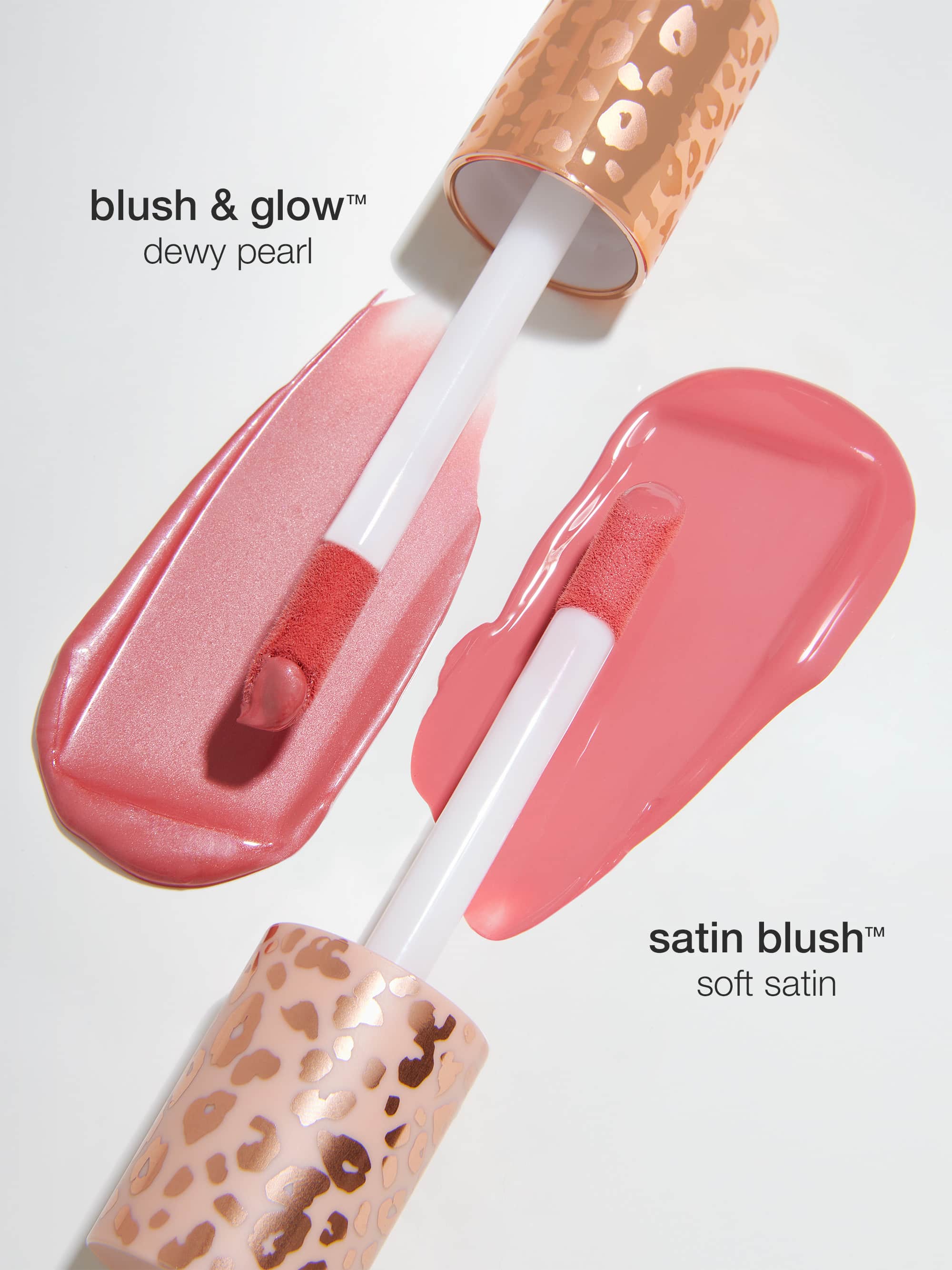 Two lip gloss applicators with leopard print handles lay on a white surface, showcasing swatches. Text reads: blush & glow™ dewy pearl and satin blush™ soft satin.