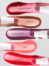 Five tarte maracuja juicy lip plumping oil with applicators labeled 'honesuckle', 'sienna', 'boysenberry', 'rose', and 'cherry' on a light gray background.