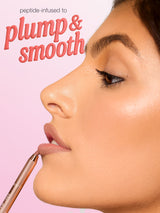 Close-up profile of a woman's lips as a Tarte lip pencil outlines them, applying liner against a soft pink background. Text: peptide-infused to plump & smooth