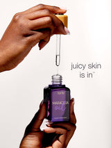 Hand holding a bottle of tarte Maraculiu oil with a dropper, against a white background.