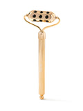 Gold facial roller with black stones on a white background
