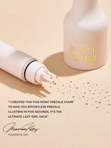 Five-prong freckle stamp presses tiny pigment dots beside a Tarte Go With The Faux bottle on beige paper, creating scattered faux freckles. Text: tarte™ GO WITH THE FAUX I CREATED THIS FIVE-POINT FRECKLE STAMP TO GIVE YOU EFFORTLESS FRECKLE CLUSTERS IN FIVE SECONDS. IT'S THE ULTIMATE LAZY GIRL HACK Maureen Kelly FOUNDER & CEO