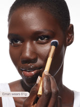 Woman applying makeup with a brush on a white background