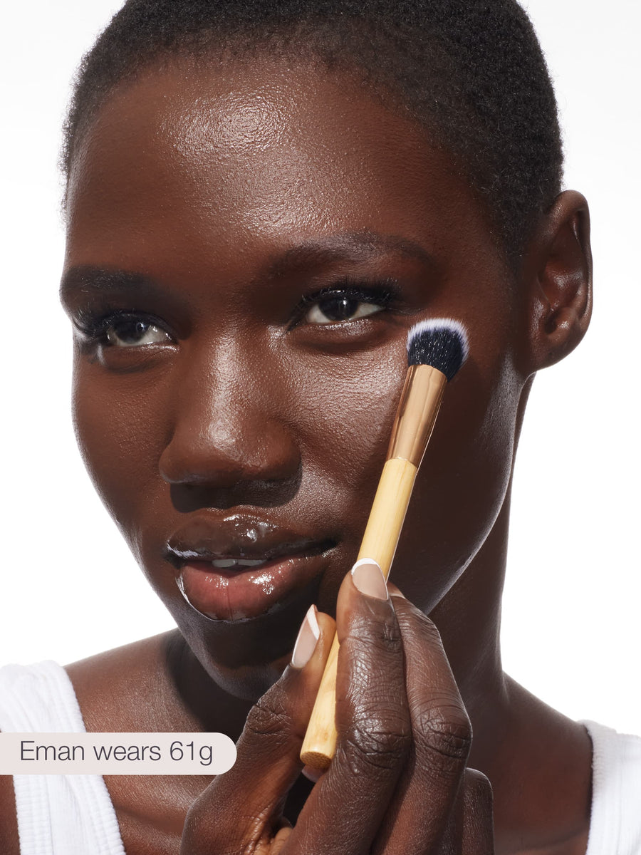 Woman applying makeup with a brush on a white background