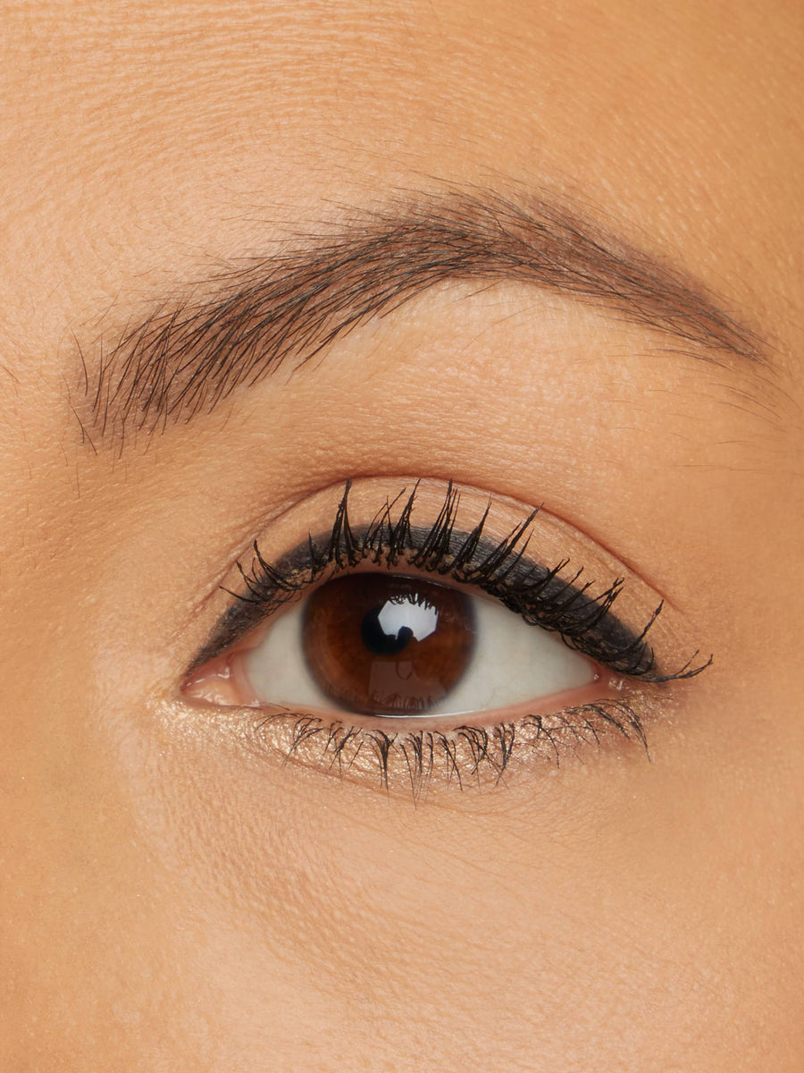 Close-up of a brown eye with eyeliner and mascara on a beige background