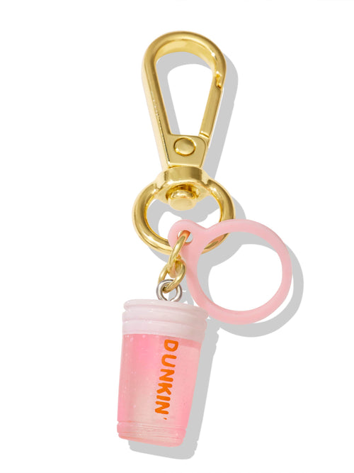 A gold keychain features a small pink plastic cup charm with DUNKIN' printed in orange. The cup resembles a beverage with bubbles inside, attached to a pink circular ring.