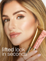 Woman holding a lip gloss with a visible brand logo