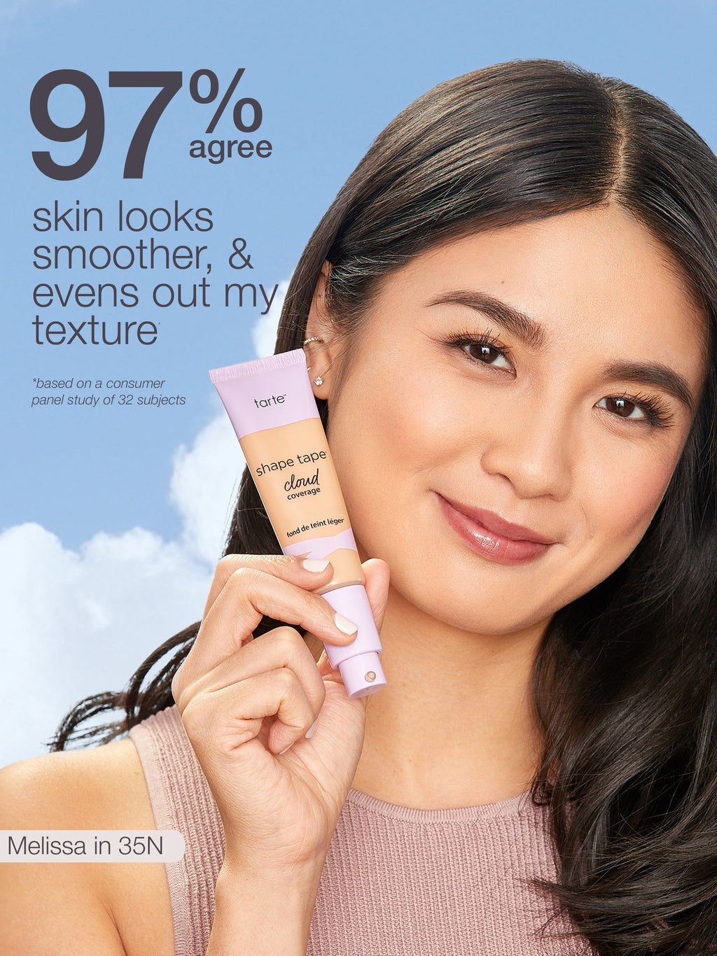 Woman holding a pink skincare product with text about skin texture improvement against a blue sky. using Tarte shape tape cloud coverage 