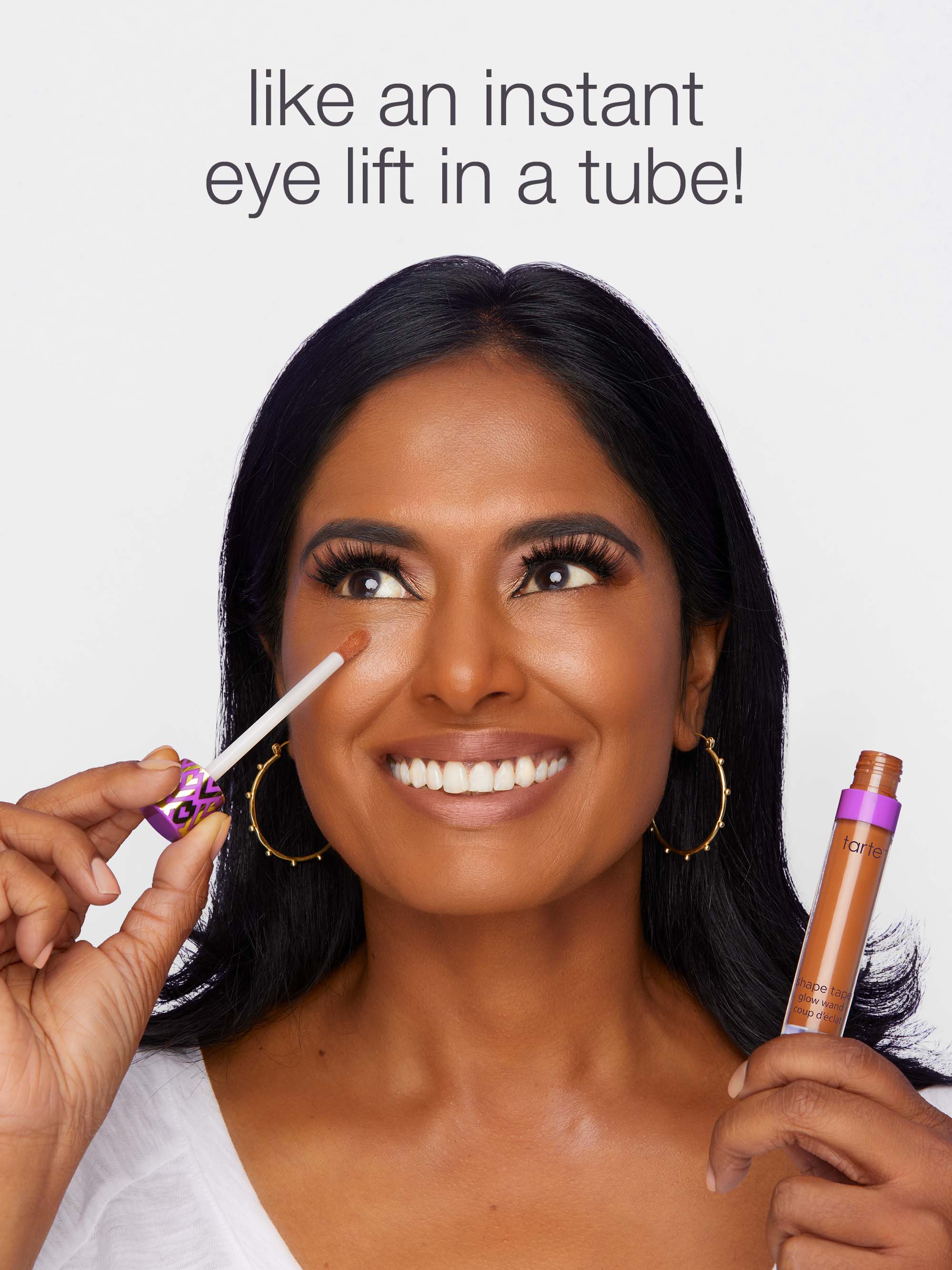 Woman applying makeup with a product labeled 'like an instant eye lift in a tube!' on a light gray background