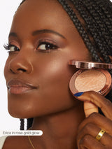 Woman applying rose gold glow makeup to her face