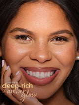 Close-up of a woman's face with 'Carolina Herrera Deep Rich Amber Glow' makeup. using tarte cosmetics freckle stick