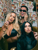 Three people posing together in a room with colorful wall art.