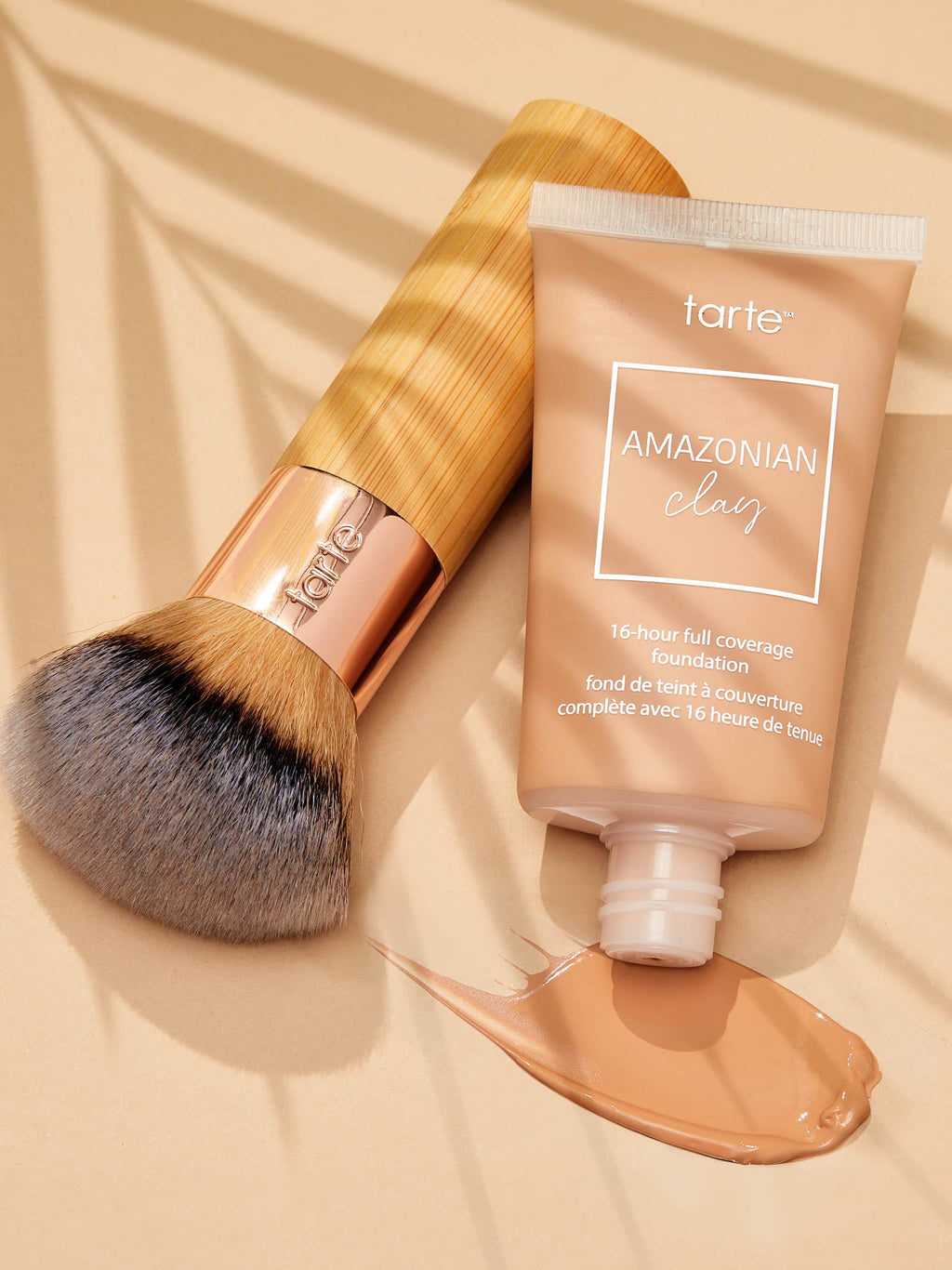 Tarte Amazonian Clay foundation tube with brush on a beige background