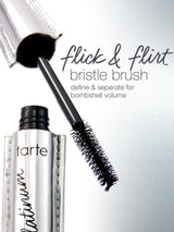 A mascara wand extends from a metallic tube labeled tarte platinum, with text beside it: flick & flirt bristle brush define & separate for bombshell volume. The background is light gray.
