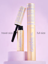 Mascara tubes labeled “tartelette XL tubing mascara” stand on a purple platform. One travel-size tube is open, revealing the wand. Text: travel-size and full-size. Background is a soft lavender.