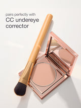 Makeup product with brush and text 'pairs perfectly with CC undereye corrector' on a light background
