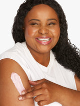Woman applying cream to her arm against a white background