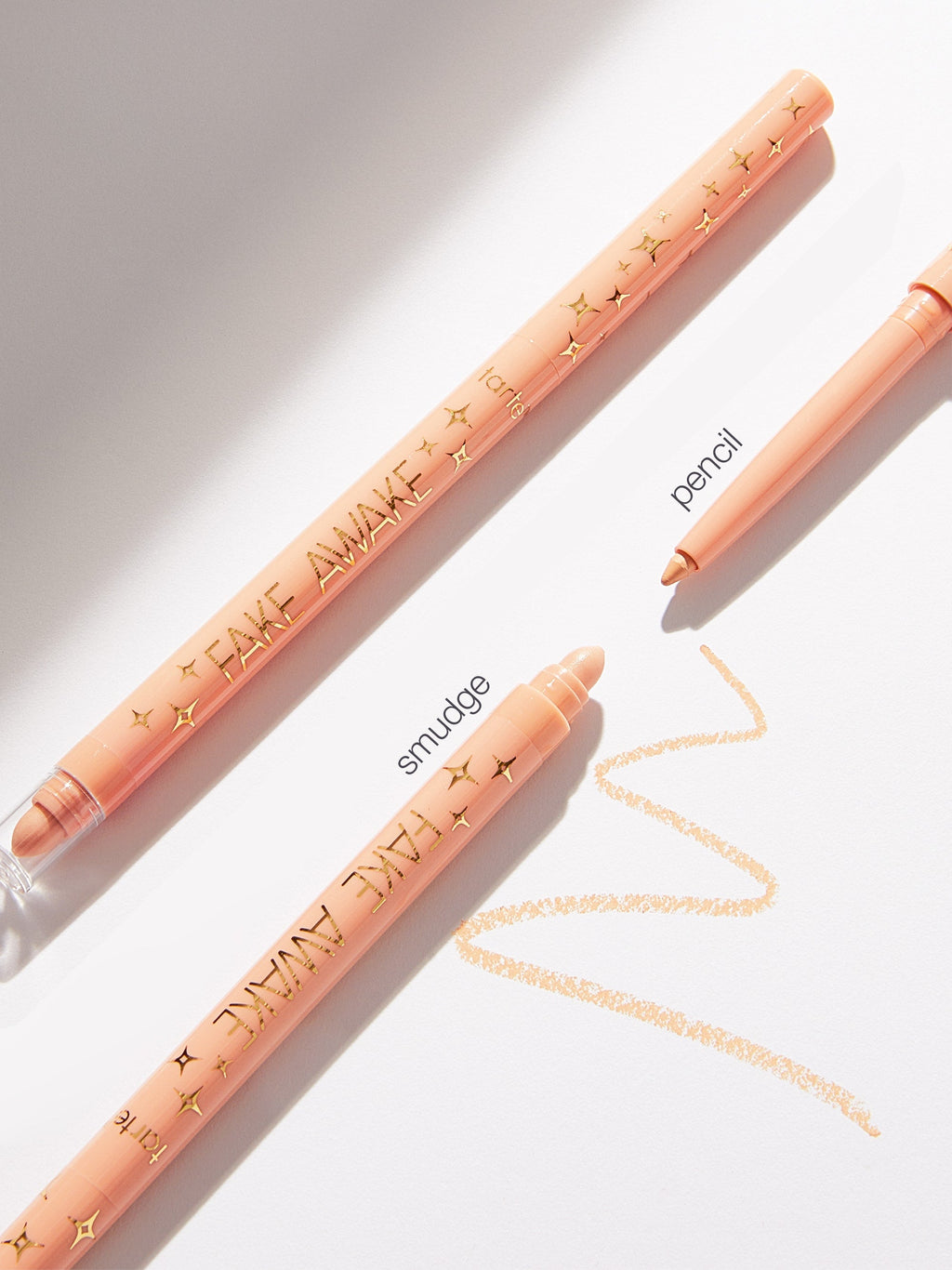 Two peach-colored makeup pencils with text on a light background