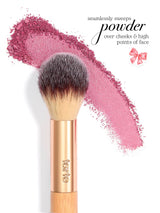 Tarte makeup brush sweeps crushed pink powder across a white background; text reads seamlessly sweeps powder over cheeks & high points of face. A small pink bow graphic appears near the text.