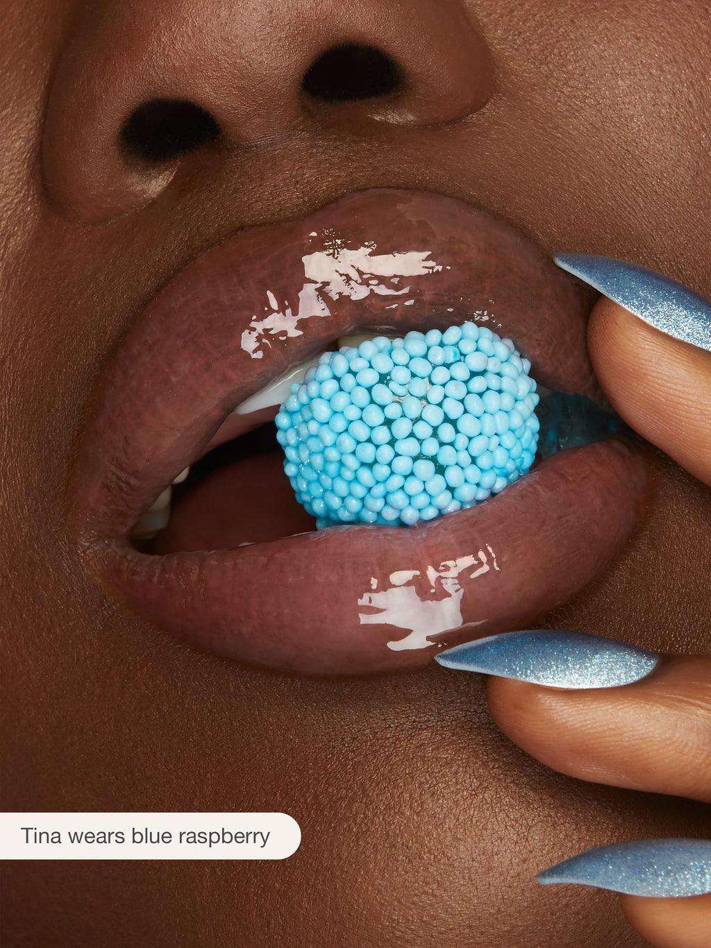 Close-up of a person's mouth with blue raspberry lip product on lips and nails.