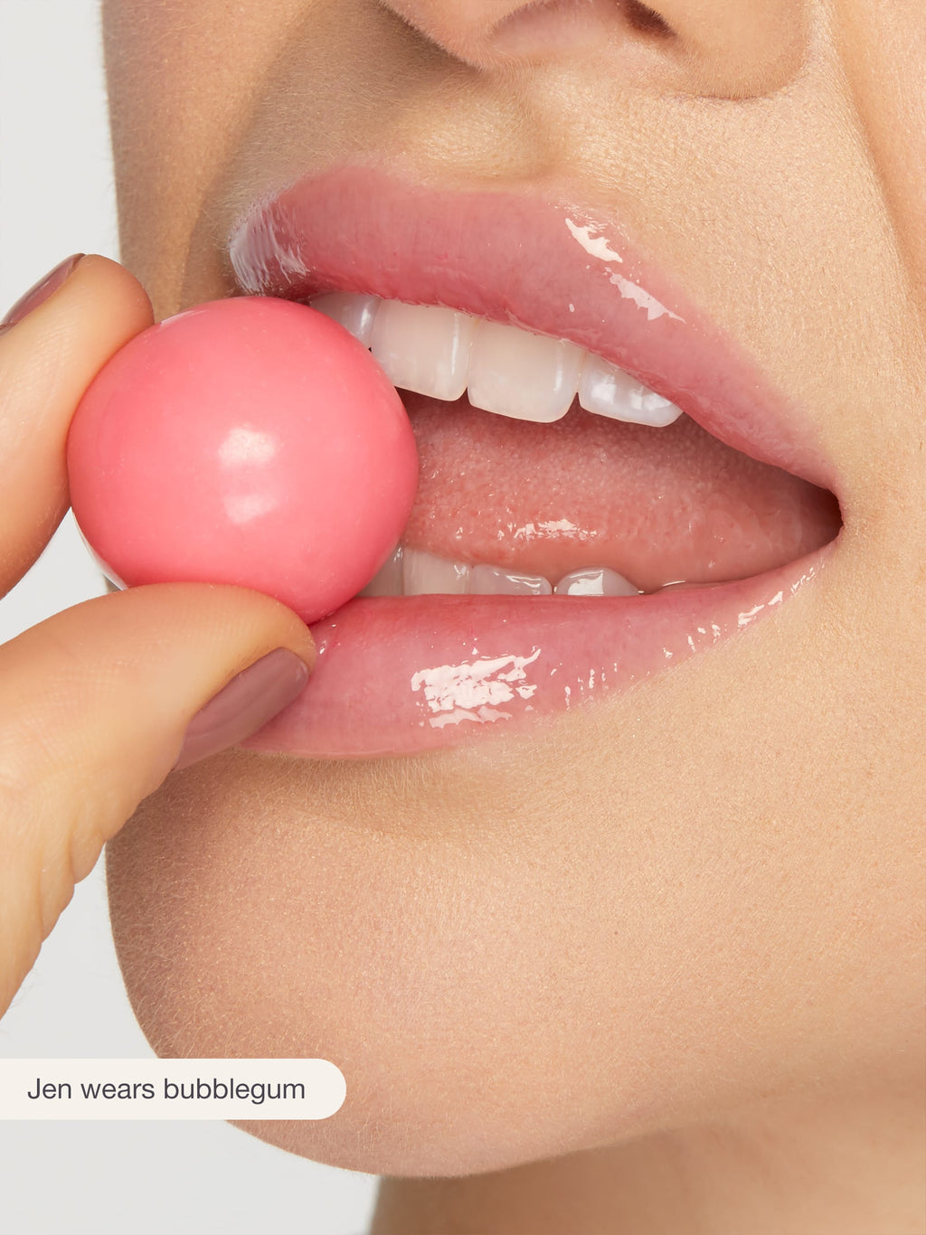 Close-up of a person's lips with a pink bubblegum, wearing a glossy lip color.