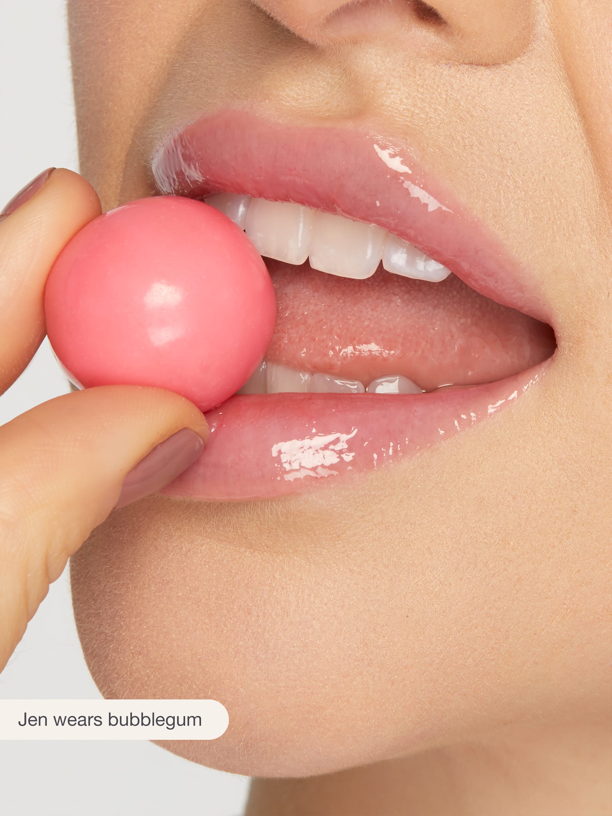 Close-up of a person's lips with a pink bubblegum, wearing a glossy lip color.