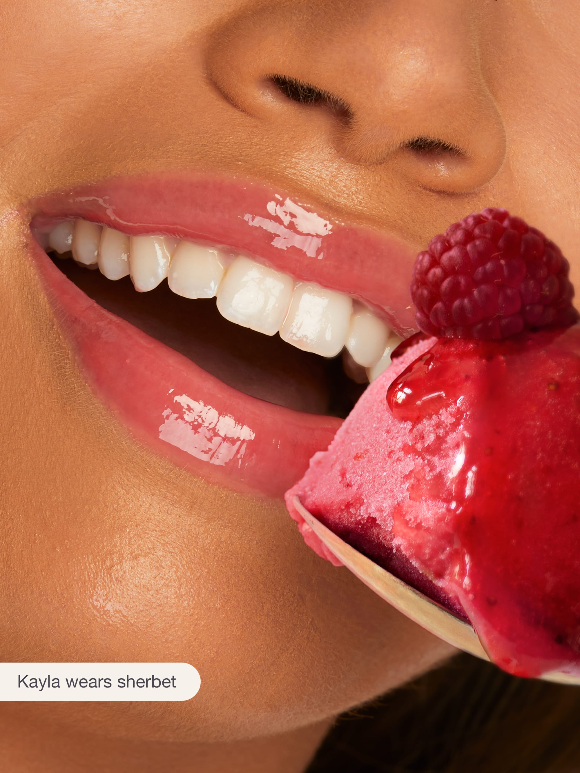 Close-up of a person eating a raspberry sherbet ice cream cone with a visible brand name.