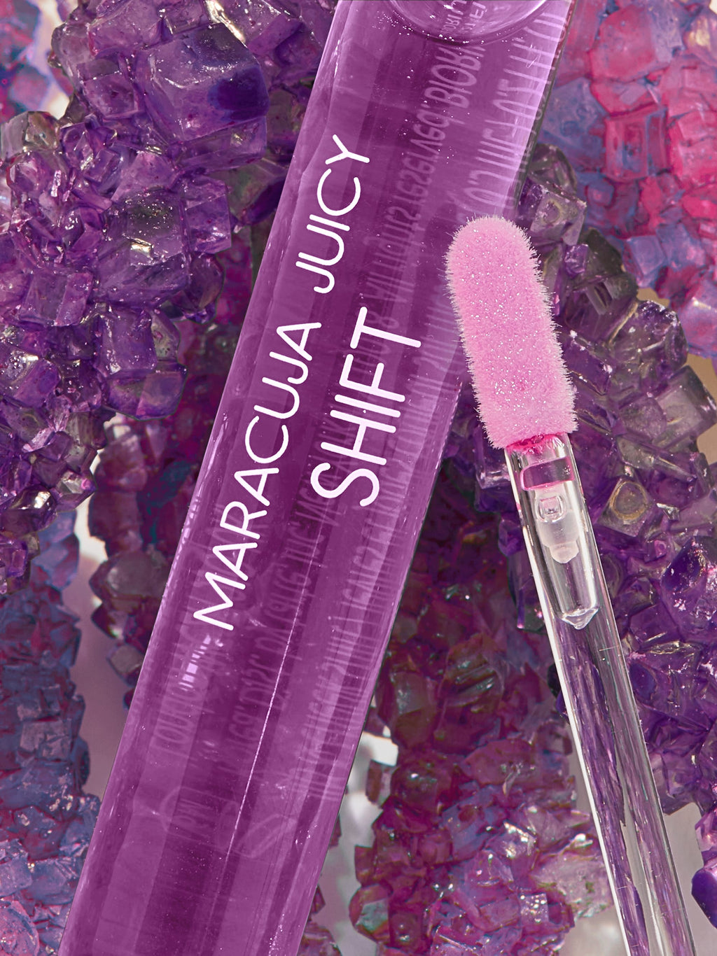 Purple lip gloss with a brush on a colorful gemstone background