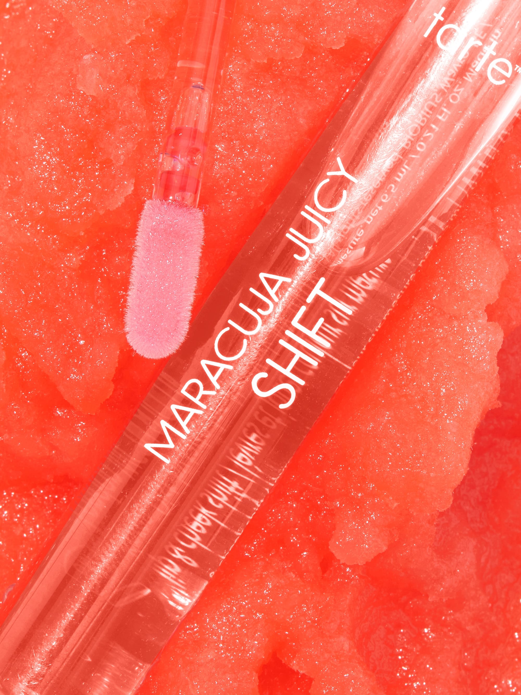 Tarte lip product with pink applicator on a red textured background