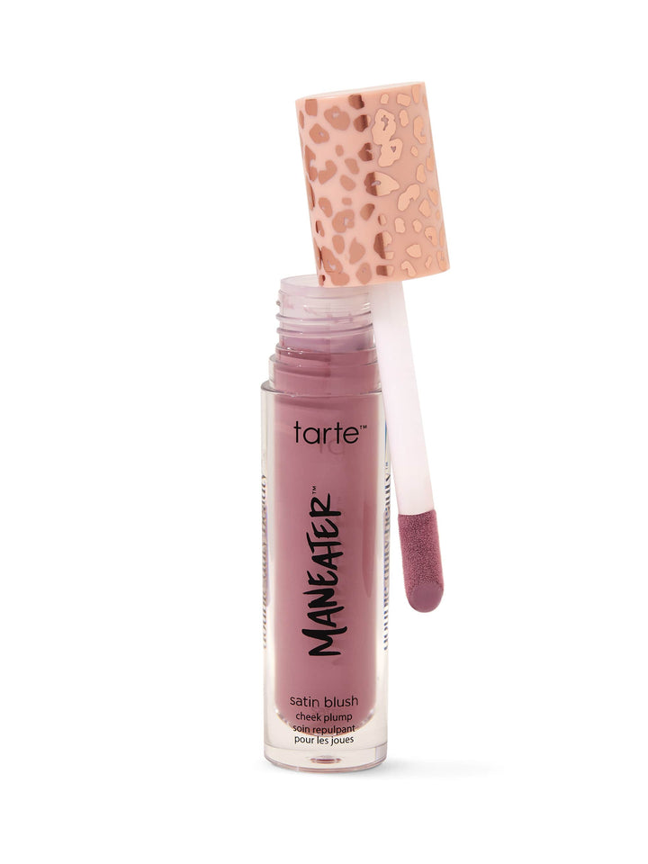 A lip gloss bottle stands upright, partially opened, with an applicator leaning against it. The label reads WONDER. The cap is pink with a speckled design, set against a plain white backdrop.