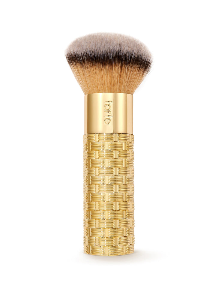Makeup brush with gold handle and textured design on a white background