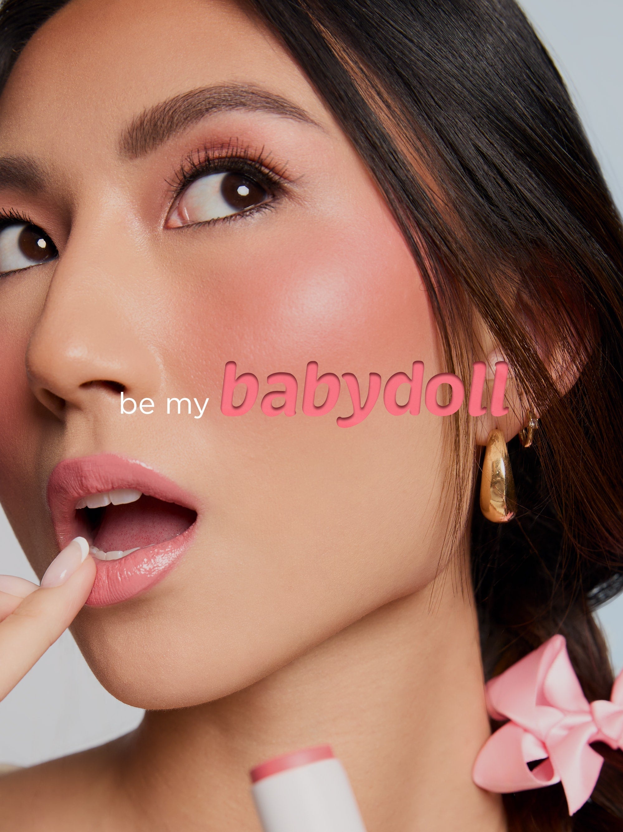 Close-up of a woman's face with makeup products and 'be my babydoll' text.