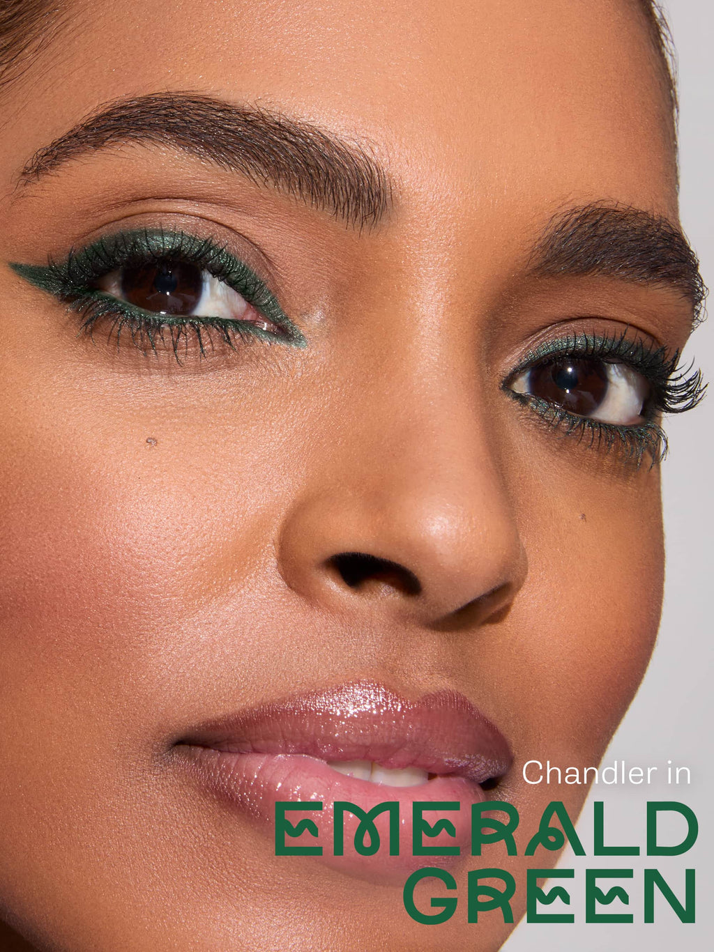 Close-up of a person applying eyeliner with a brush, featuring the brand 'Chandler' in Emerald.