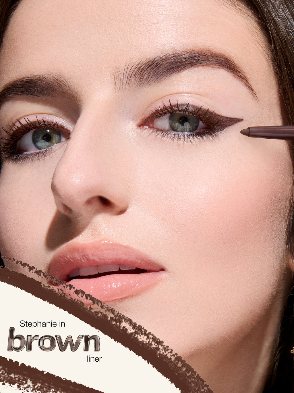 Close-up of a woman applying brown eyeliner with a brush.