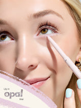 Woman applying eyeliner with a pencil, focusing on eye makeup.