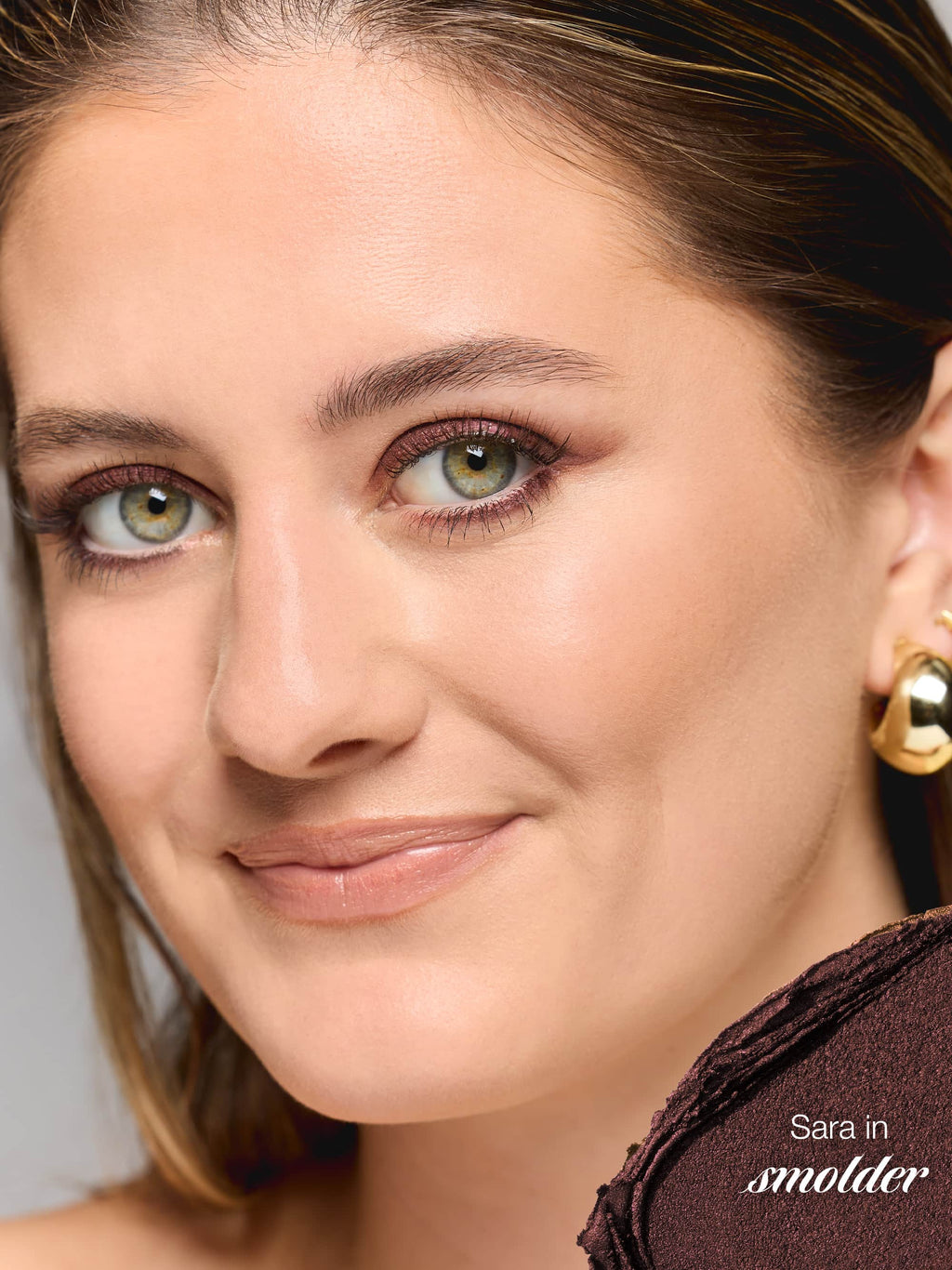Close-up of a woman wearing gold earrings with a neutral background