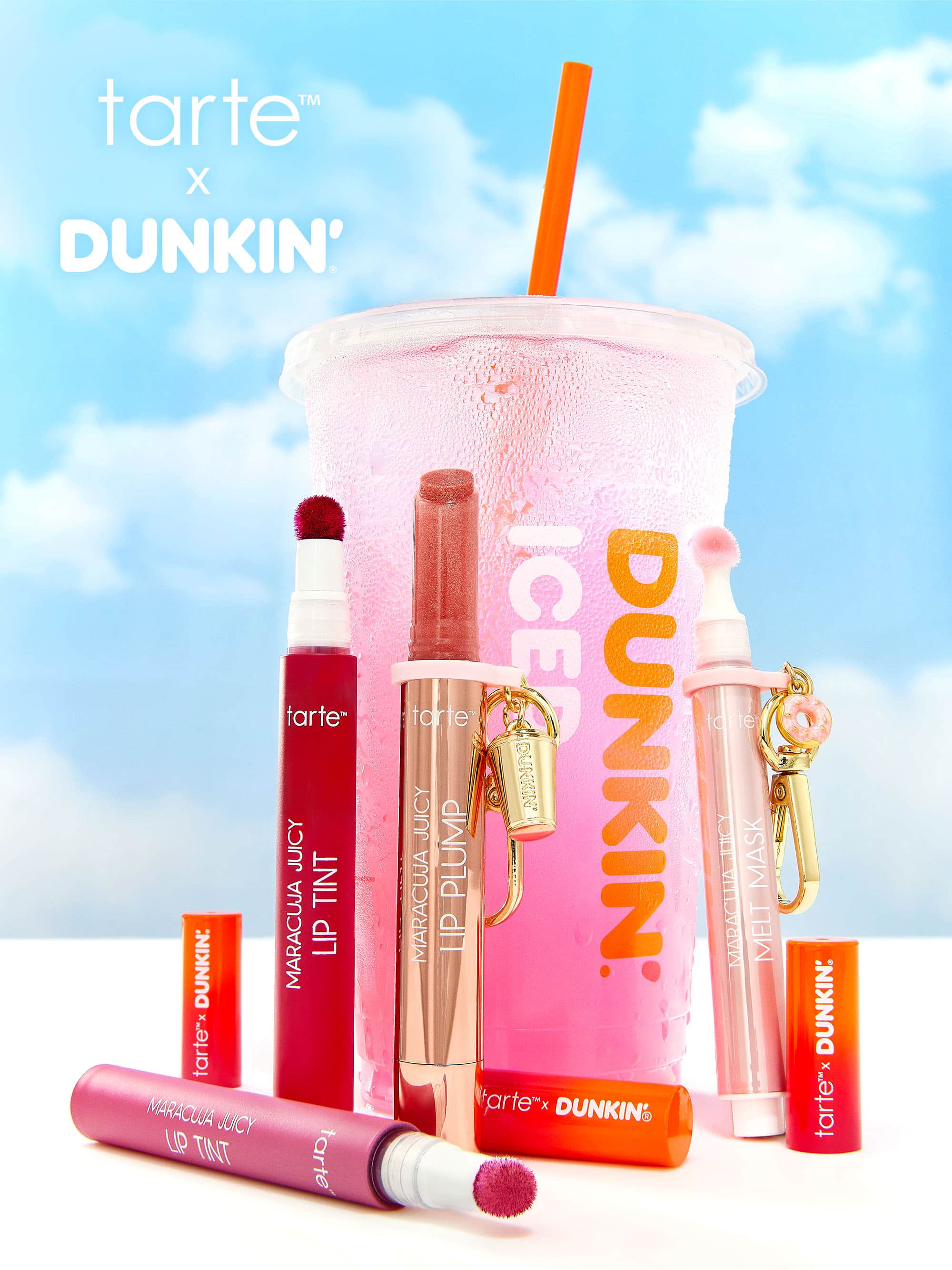 Tarte x Dunkin' lip products and a pink drink with an orange straw against a blue sky background.